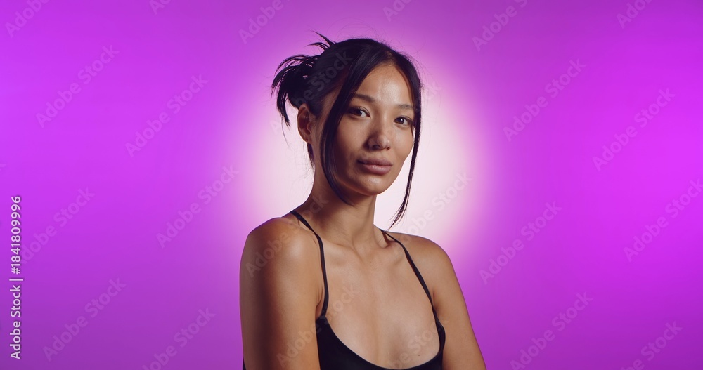 Obraz premium A young Korean model poses in a studio lit by pink neon lights