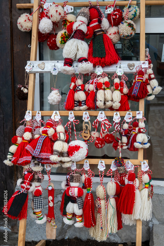 A vibrant display of handmade Martenitsa dolls and decorative charms, featuring red and white yarn, tassels, and intricate folk art designs are for sale for Baba Marta Day in Bansko, Bulgaria