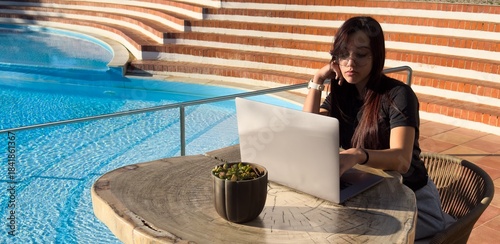 Slika na platnu Freelancer using laptop working remotely near swimming pool