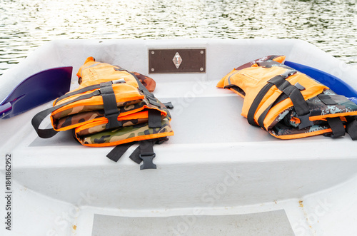 Orange life jackets on a white boat near calm water