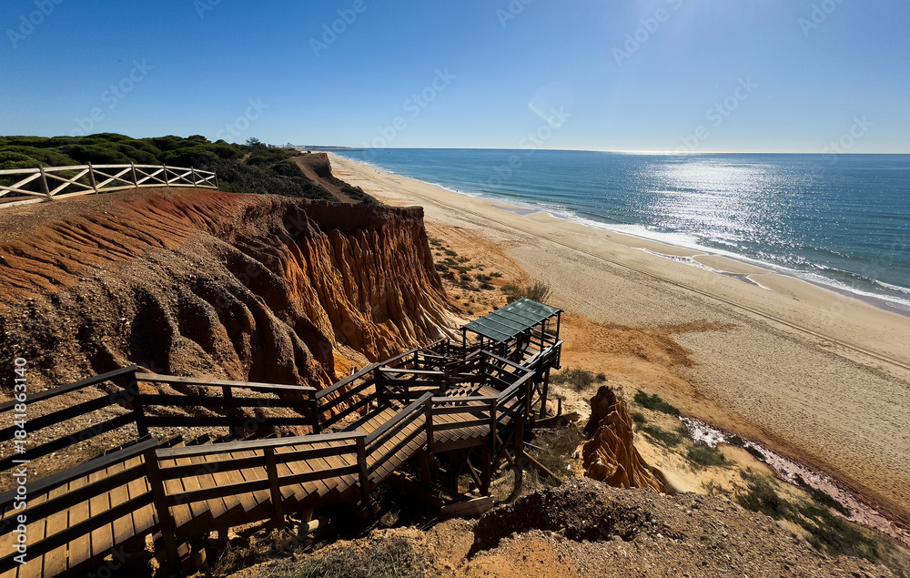 Naklejka premium A wooden staircase with handrails leads to the ocean.