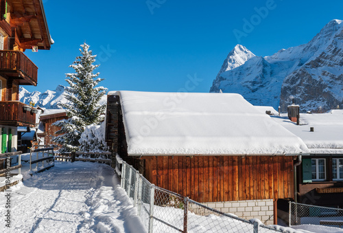 Fresh winter snow covering the alpine village and surrounding peaks, creating a bright and peaceful mountain landscape