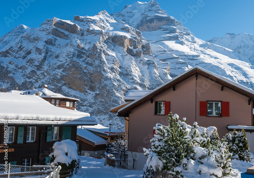 Fresh winter snow covering the alpine village and surrounding peaks, creating a bright and peaceful mountain landscape