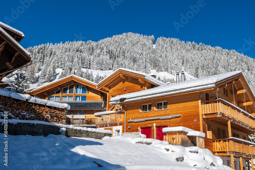 Fresh winter snow covering the alpine village and surrounding peaks, creating a bright and peaceful mountain landscape