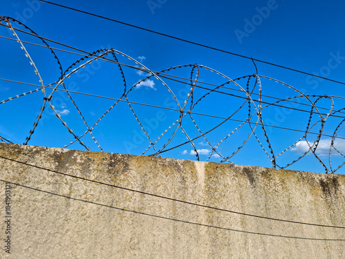 Metal barbed wire is stretched on a concrete fence