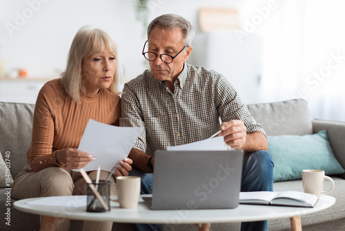 Photography An older couple sits closely on a sofa reviewing important documents