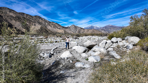 A Woman Geologist on the Trail in the Whitewater Canyon in California evaluating weathering, Erosion, and Runoff along the Whitewater River near Palm Springs to evaluate flood potential