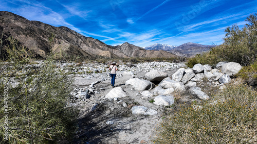 A Woman Geologist on the Trail in the Whitewater Canyon in California evaluating weathering, Erosion, and Runoff along the Whitewater River near Palm Springs to evaluate flood potential
