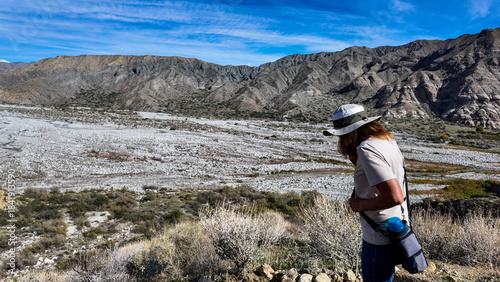 A Woman Naturalist on the Trail at Whitewater River in Palm Springs, California,  Exploring the Terrain and Habitat to teach guests and students about the Environment in a rock stream bed