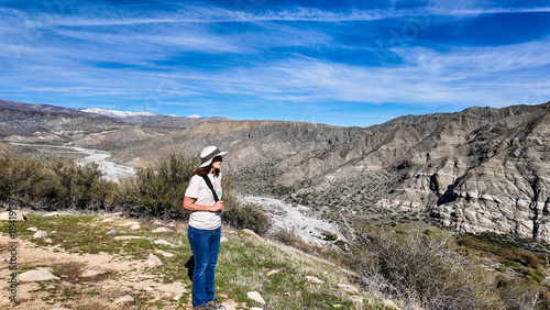 A Woman Naturalist on the Trail at Whitewater River in Palm Springs, California,  Exploring the Terrain and Habitat to teach guests and students about the Environment in a rock stream bed