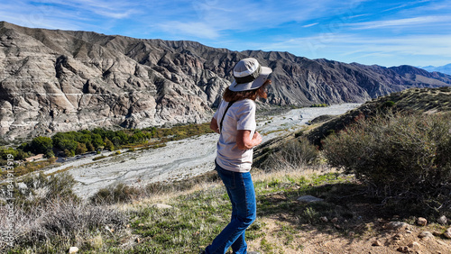 A Woman Naturalist on the Trail at Whitewater River in Palm Springs, California,  Exploring the Terrain and Habitat to teach guests and students about the Environment in a rock stream bed