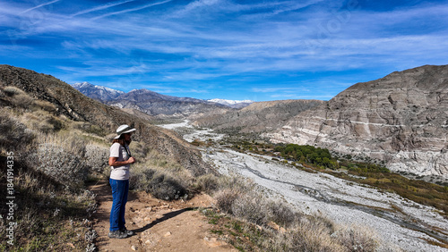 A Woman Naturalist on the Trail at Whitewater River in Palm Springs, California,  Exploring the Terrain and Habitat to teach guests and students about the Environment in a rock stream bed