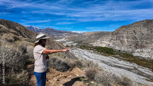 A Woman Naturalist on the Trail at Whitewater River in Palm Springs, California,  Exploring the Terrain and Habitat to teach guests and students about the Environment in a rock stream bed
