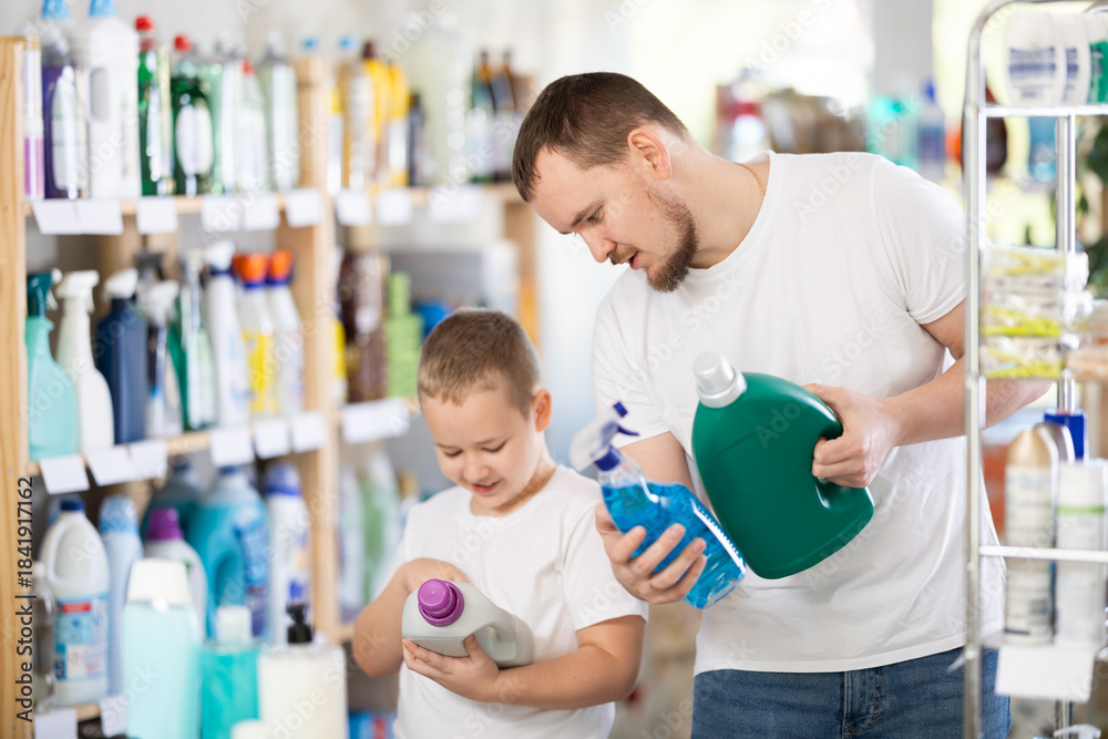 Fototapeta premium Young man with boy shoppers buying laundry detergent in household chemicals store