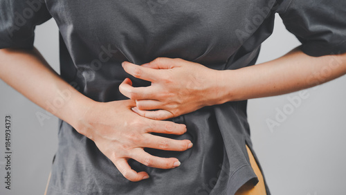 Schilderij op canvas Close-up of a woman clutching her stomach with both hands, depicting abdominal pain or discomfort, ideal for health and medical-related content