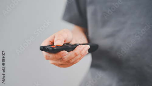 Close-up of a hand holding and pressing a remote control, symbolizing modern convenience, smart living, and home electronics interaction.