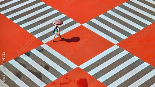 A Person Walking With An Umbrella Across A Vibrant Red And White Crosswalk