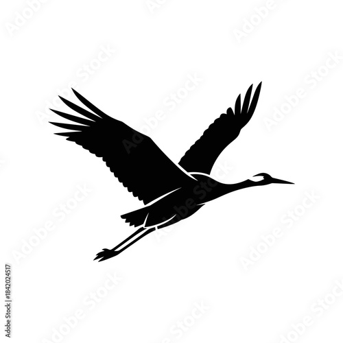 Black silhouette of a crane bird in graceful flight with wings spread wide against a plain background.