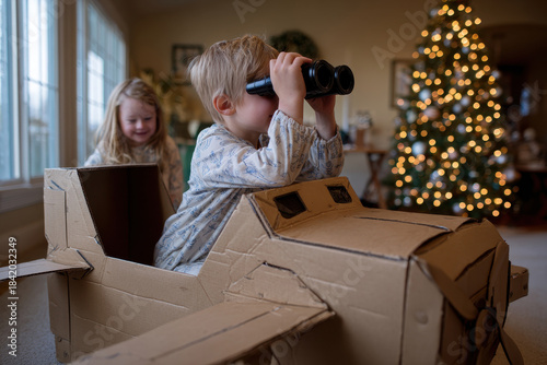 Child boy plays in toy plane against background of Christmas decorations.
