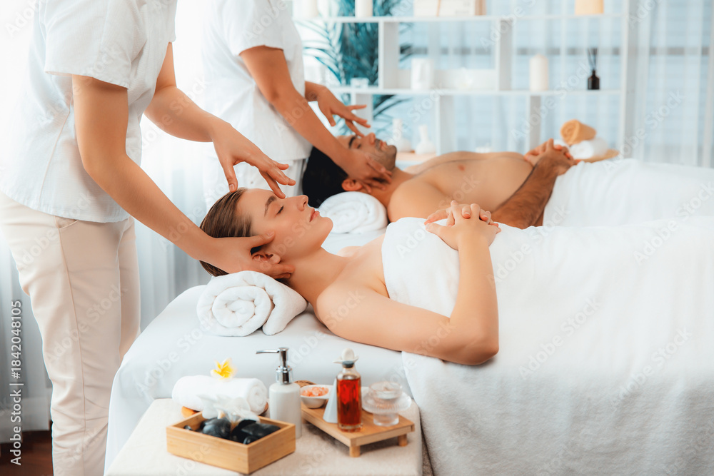 Obraz premium Caucasian couple enjoying relaxing anti-stress head massage and pampering facial beauty skin recreation leisure in dayspa modern light ambient at luxury resort or hotel spa salon. Quiescent