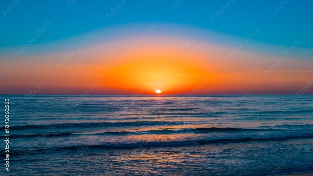 Obraz premium Breathtaking Symmetrical Ocean Sunrise or Sunset with Vibrant Blue and Orange Sky