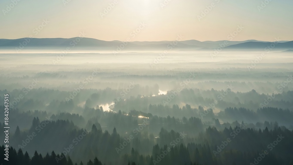 Naklejka premium Misty Morning Landscape with Foggy Valley and Distant Mountains at Sunrise.