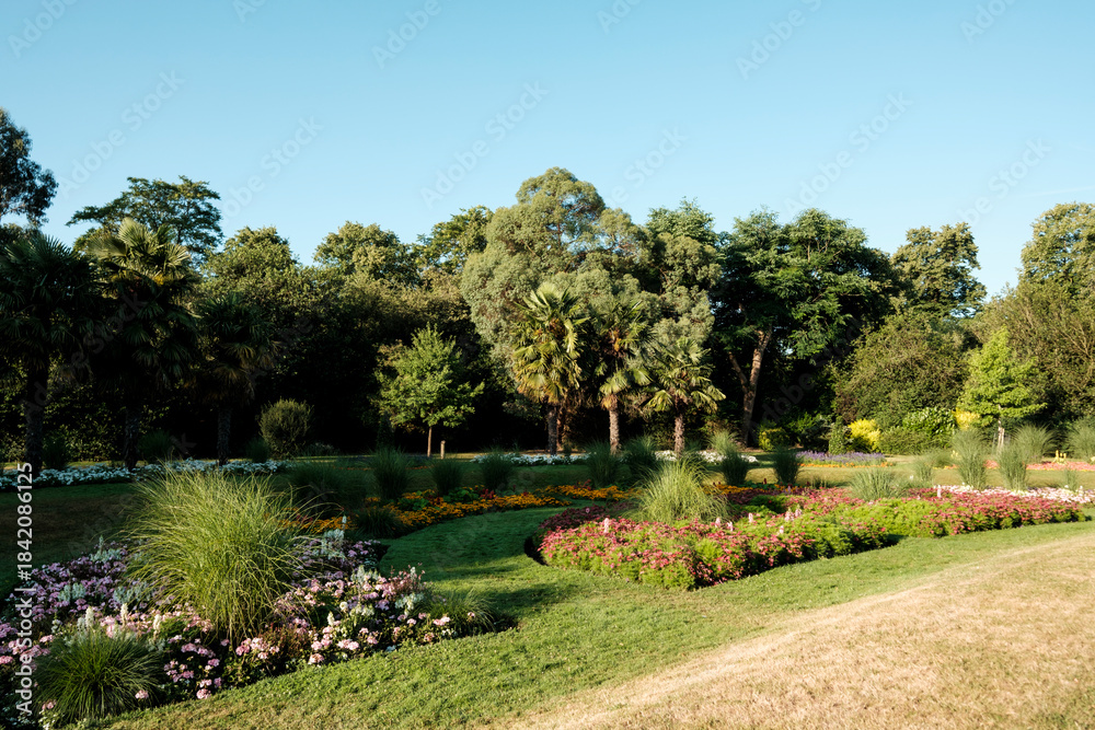 Obraz premium Lush ornamental park displaying vibrant flowerbeds and green trees