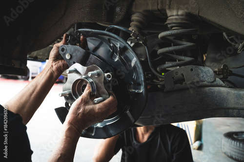 Auto mechanic installing a new wheel hub bearing , wheel hub bearing replacement in garage service shop.