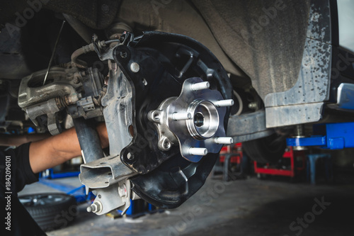 Auto mechanic installing a new wheel hub bearing , wheel hub bearing replacement in garage service shop.
