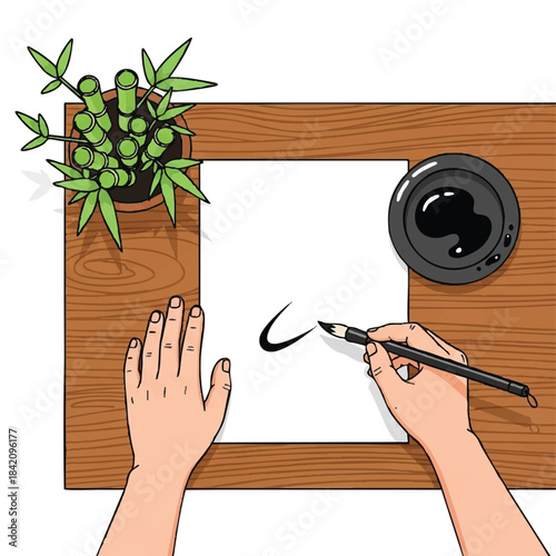 Overhead view of a person's hands writing with a brush on paper with minimalist Chinese decorations on a wooden desk.