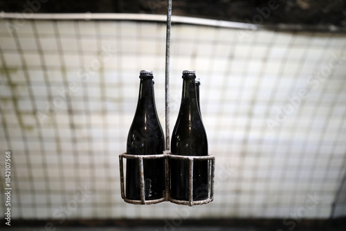 Dark glass bottles in metal rack suspended in dimly lit underground tunnel