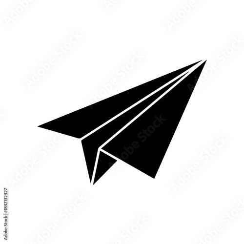 A professional businesswoman sits at a modern office desk focused on her laptop while sunlight streams through large windows