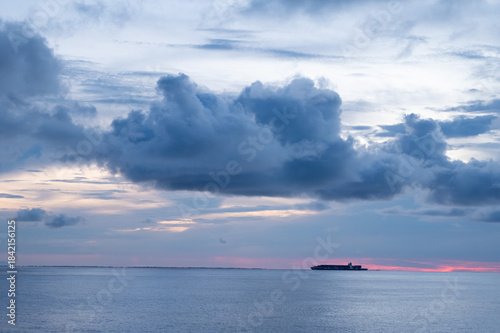Container ship with lights on at sunset