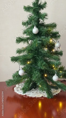Merry Christmas and Happy New Year! Time-lapse video of process of decorating an artificial Christmas tree with colorful balls and garland. Gifts in eco-friendly paper boxes with red ribbons on table 