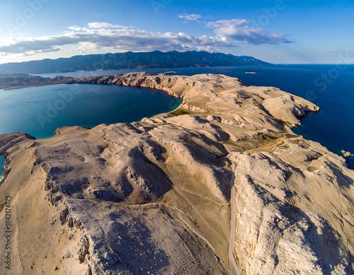 Aerial shot of rocky Croatian coastline with blue sea and mountains in the distance