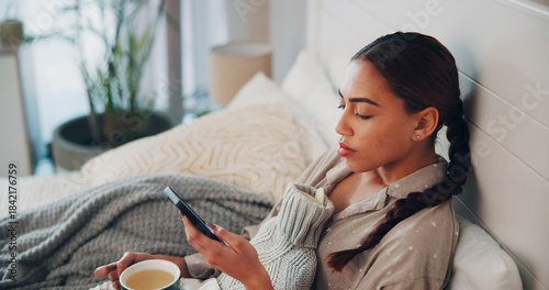 Konstfotografi Woman, phone and sick in bed with texting, herbal tea and hot water bottle for recovery in home