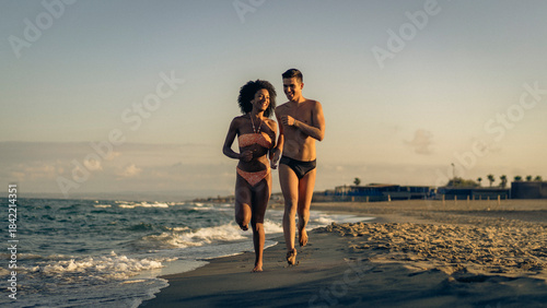 Foto A Joyful Diverse Couple Runs Barefoot Along the Beach at Golden Hour