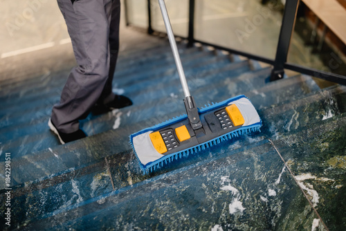 Putzkraft wischt die Treppe mit Wischmopp