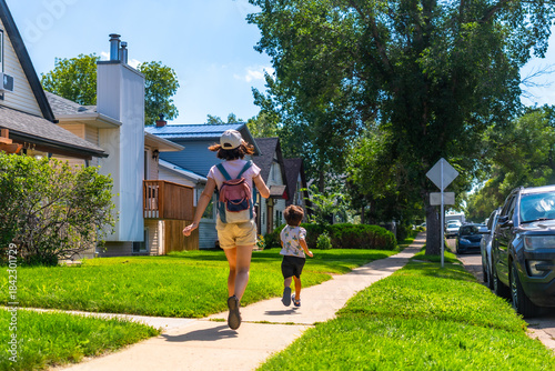 Картината върху платно Mother and son running on sidewalk in suburban neighborhood of drumheller, canad