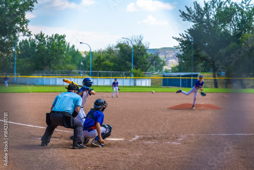 Bild auf Leinwand Young baseball pitcher throwing ball during game with batter, catcher and umpire