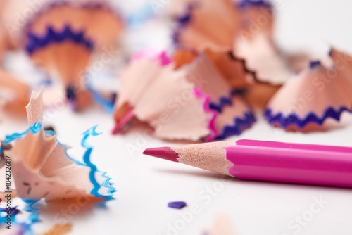 Fotografie Bright pink pencil lying on a white surface surrounded by multi-colored pencil s