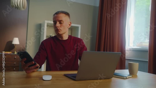 Distracted man worker remote work laptop home. Guy receive cool spicy sms mobile cell phone chatting. Male employee texting message. Ceo person take break rest. Online computer freelance distant job.