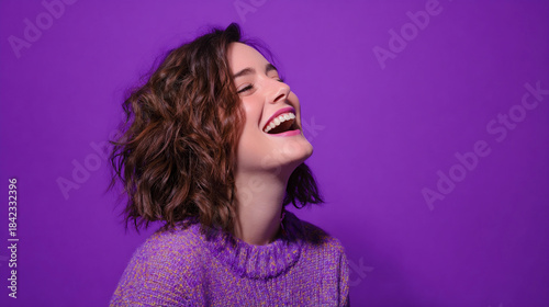 Smiling woman in purple sweater with curly hair on purple background