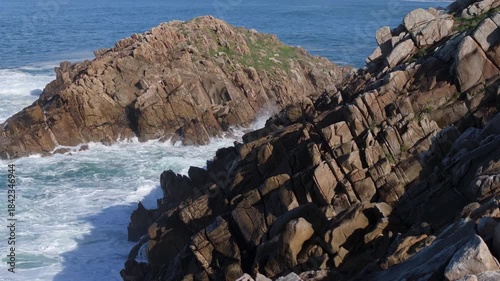 Foamy Waves Breaking Against The Rocks Of The Senda Azul (Paseo Marítimo de Arteixo) In Arteixo, A Coruña, Spain. Aerial Pullback Shot
