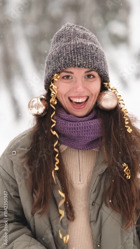 A beautiful young woman in winter clothes is happily spending her free time in a snowy forest. She enjoys the first snow. Active winter recreation.