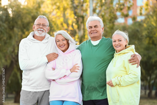 Group of sporty senior people hugging in park