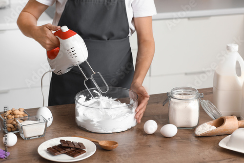 Photography Woman whipping egg albumen with mixer in kitchen