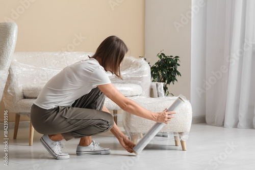 Young woman wrapping pouf w...