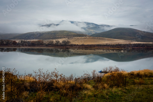 Beautiful foggy landscape in late autumn. Low clouds and riverbanks reflected in calm water of the Snake River in eastern Oregon