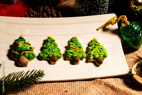  gingerbread cookies in the shape of a Christmas tree with a background of Christmas lights and decorations